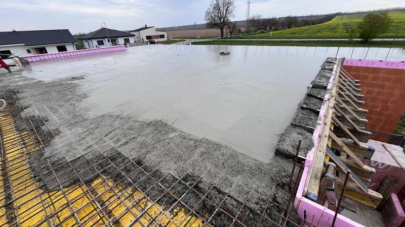 Betonáž monolitickej stropnej dosky, v pozadí okolitá zástavba a polia